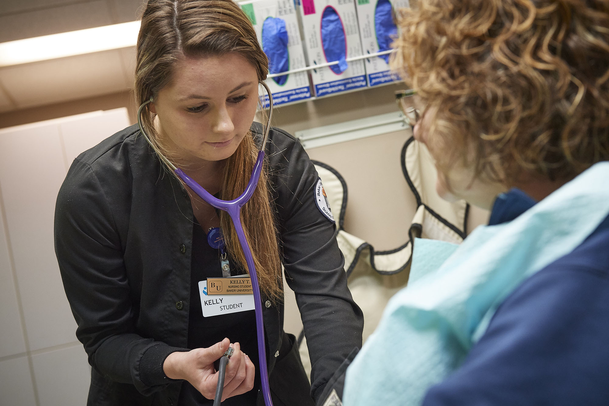 Nursing student using stethoscope to check heart beat of patient