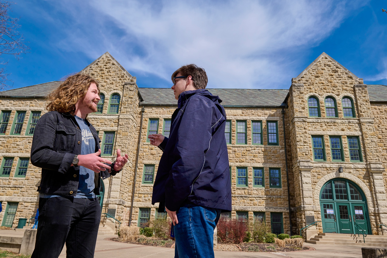 Two students talking in front of mabee hall on campus