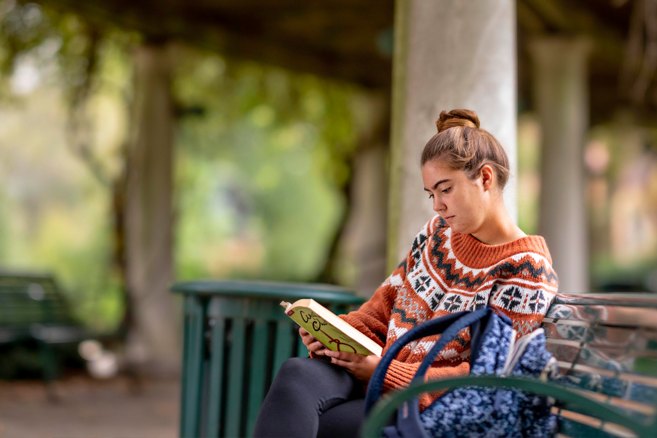 Student reading on a bench on campus