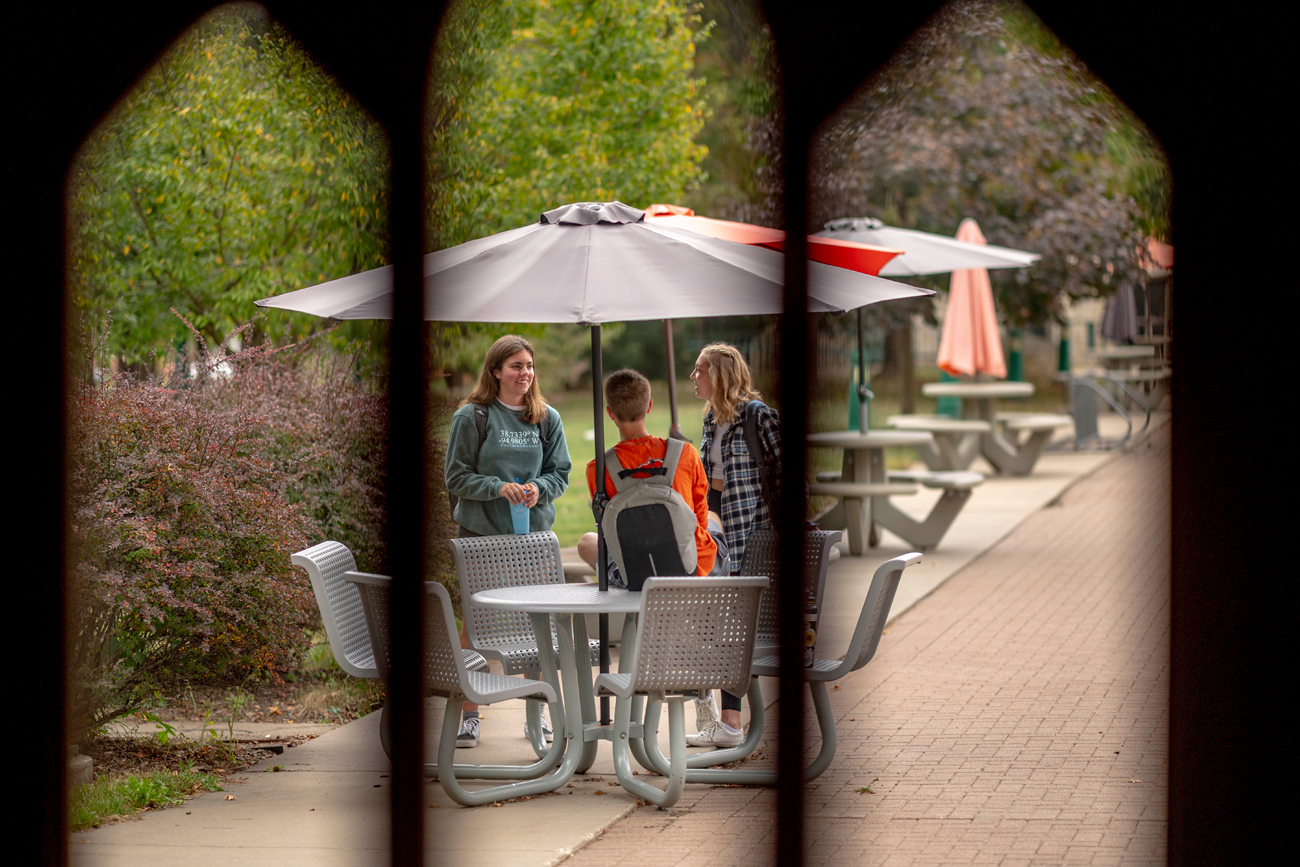 Three students talking at a table on campus