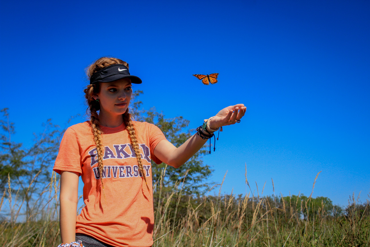 Female student catching a monarch butterfly in hand