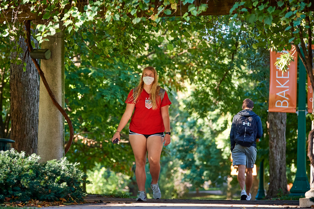 Two students walking through the grape arbor on Baker's campus