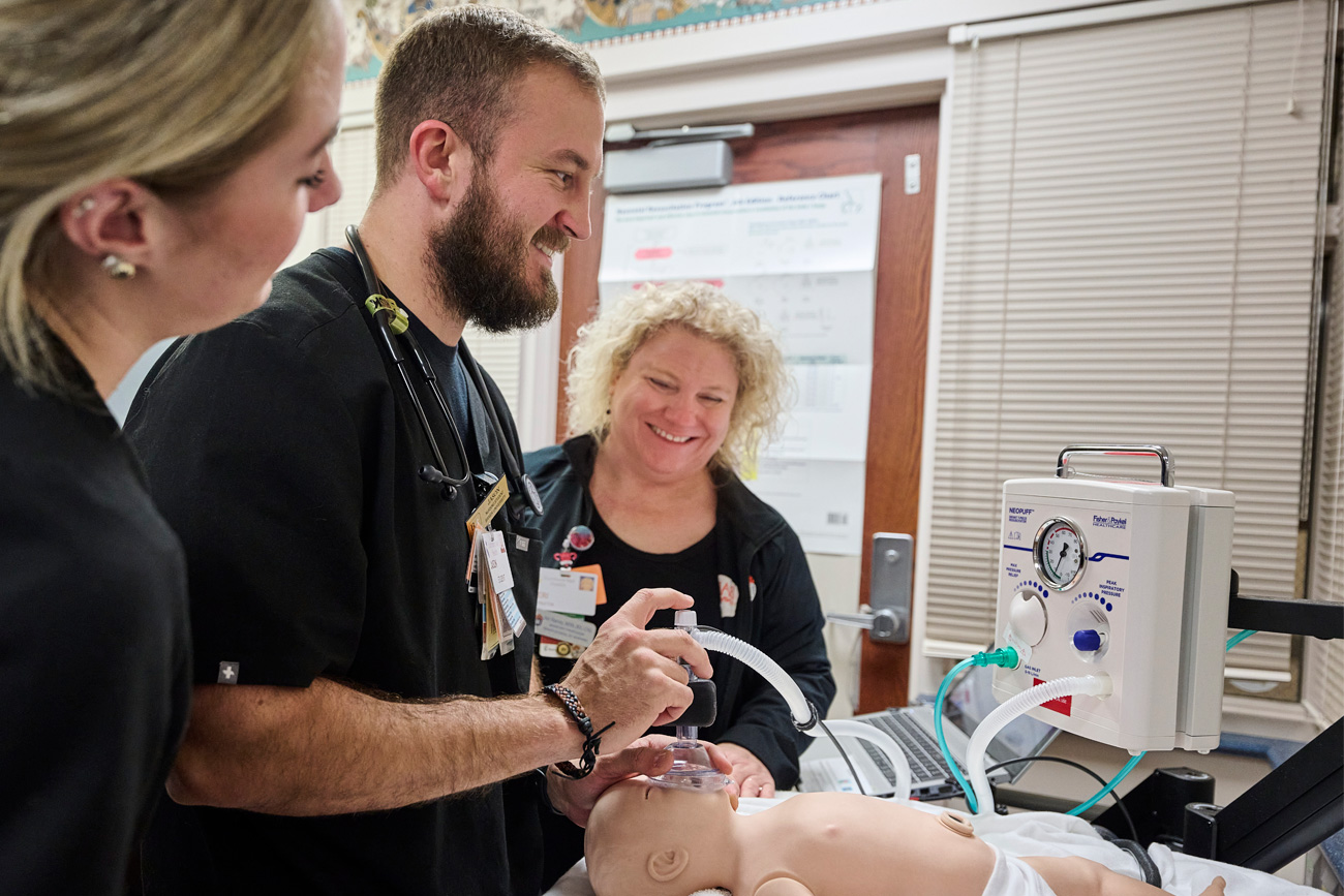 Nursing students working with baby simulation equipment to learn about newborn care.