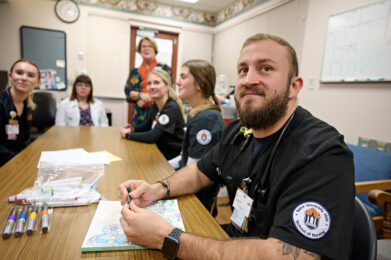 Nursing students and faculty in a meeting room.