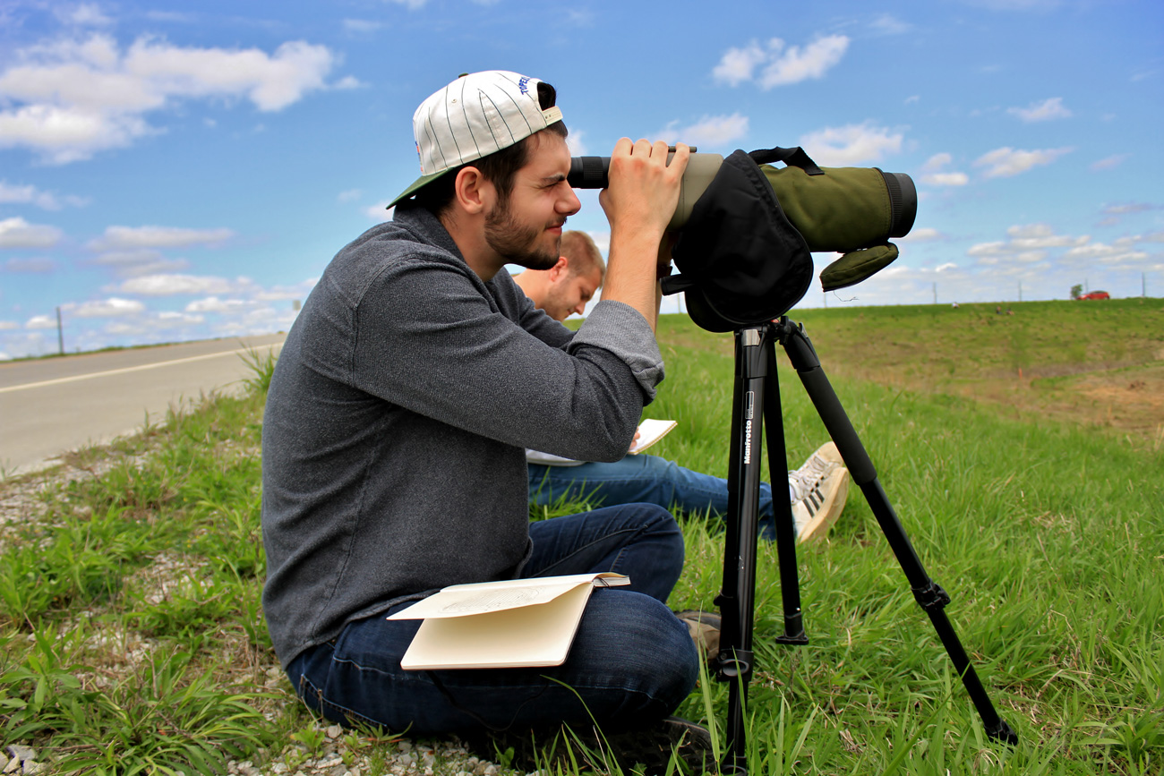 Two male students in a field looking through lens for science field work