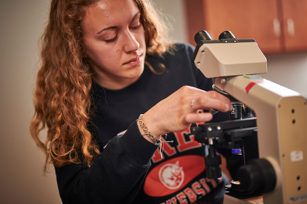 Female student looking through microscope