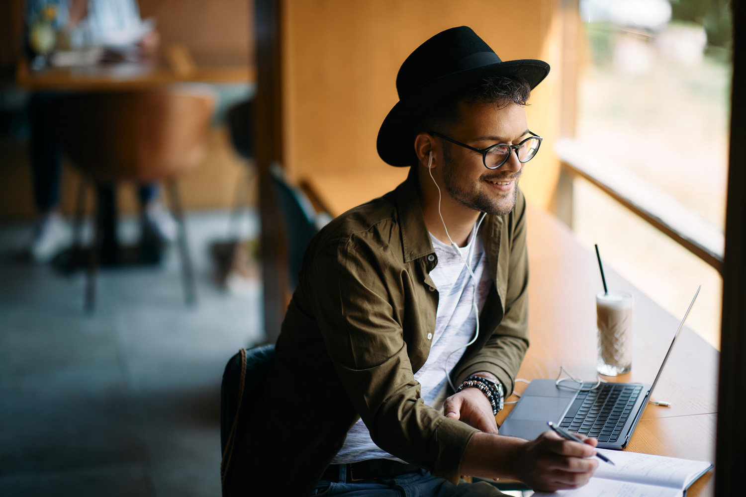 male student at laptop in coffee shop