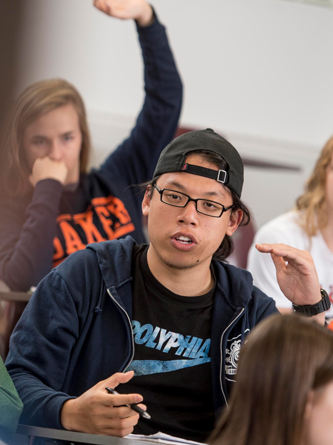 Student sitting at desks in a classroom participating