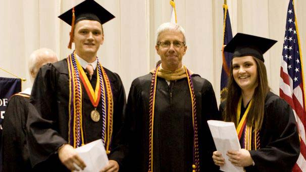 Two seniors receiving award on stage at commencement ceremony