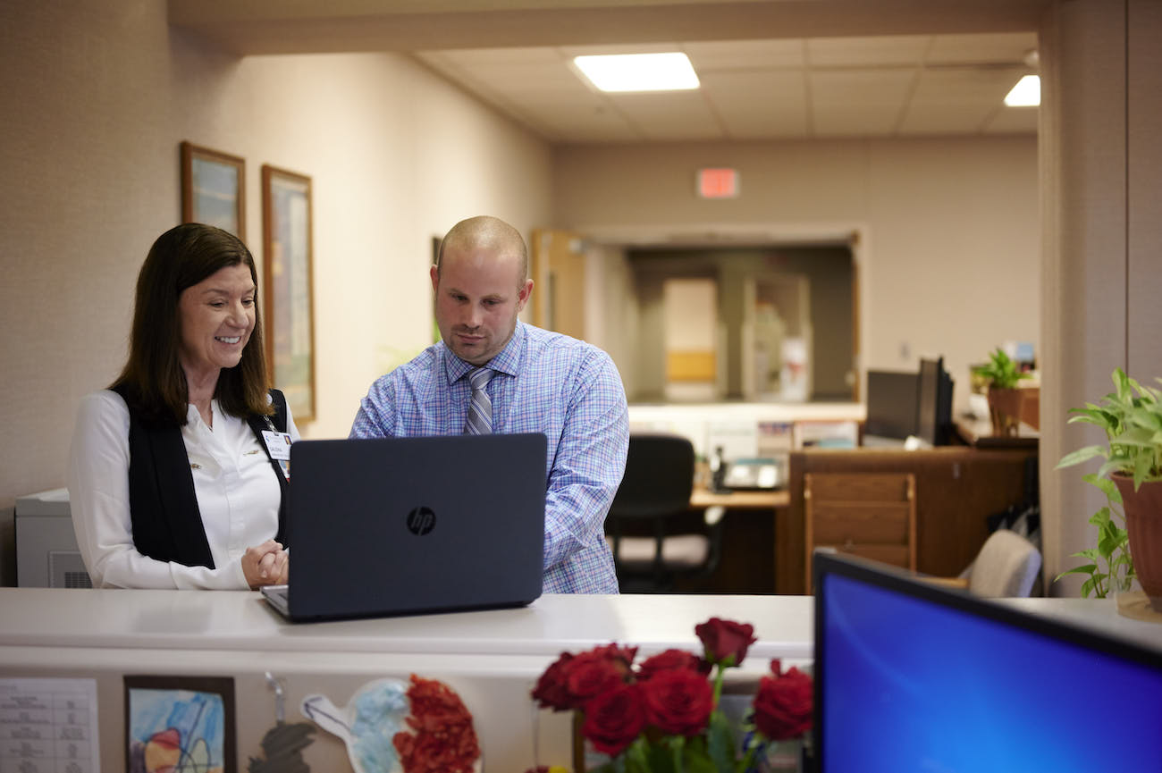Male and female nursing administrators standing at a computer
