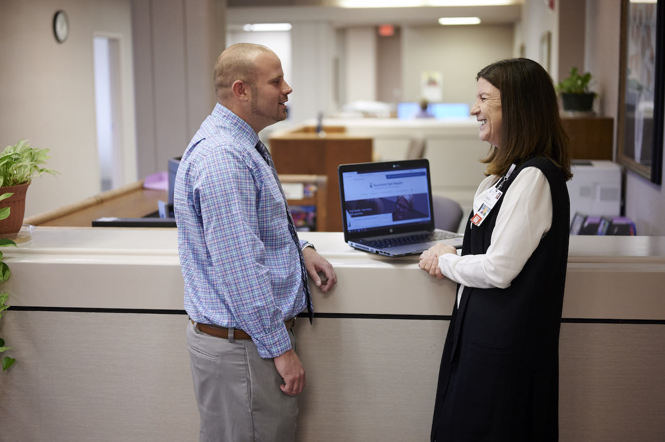 Male and female nursing administrators standing at a computer