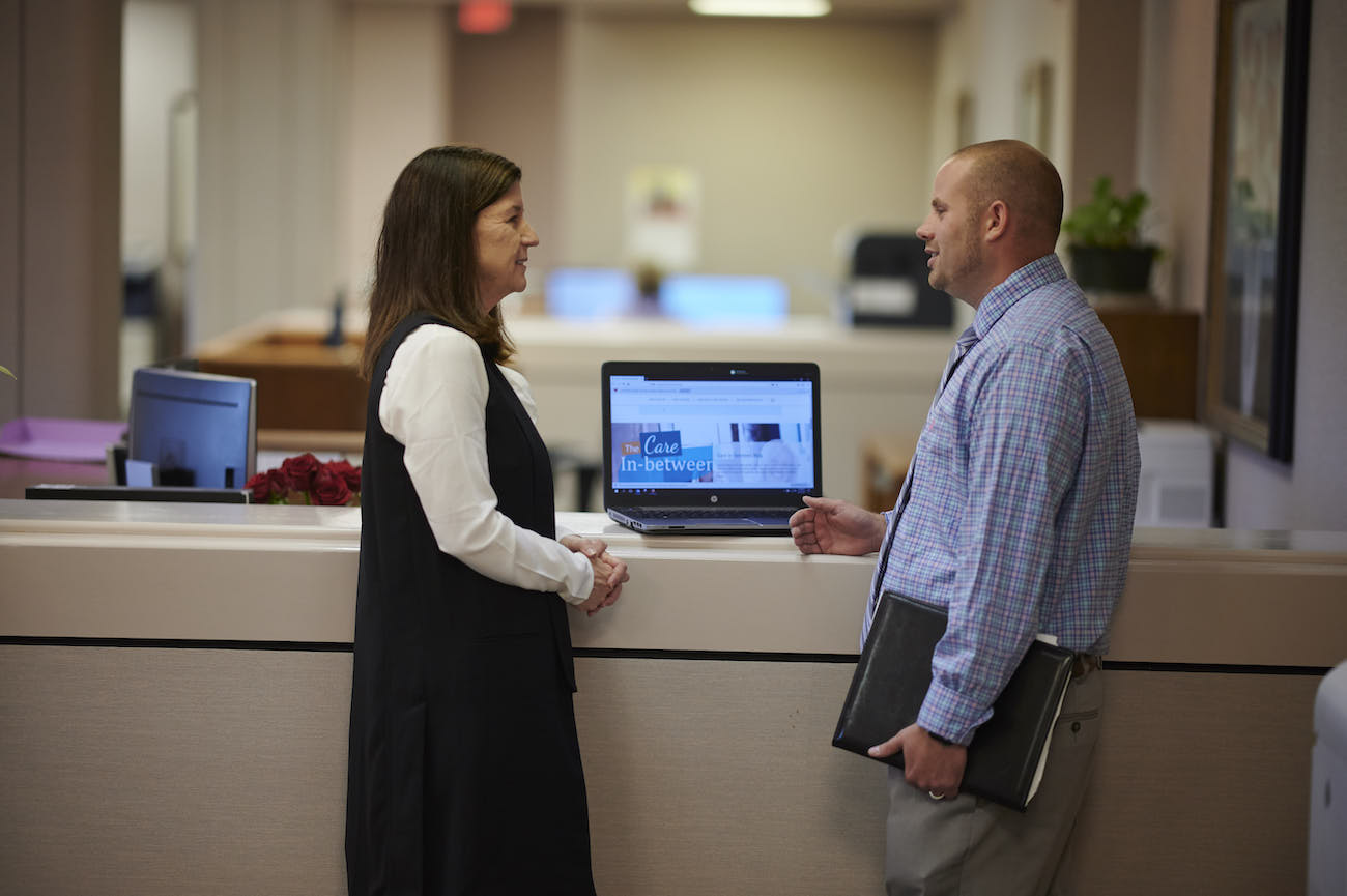 Male and female nursing administrators standing at a computer