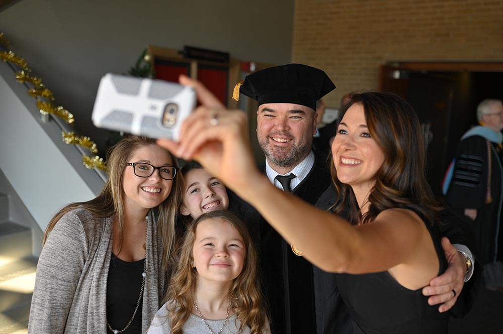 Family takes selfie after graduation celebrating the father