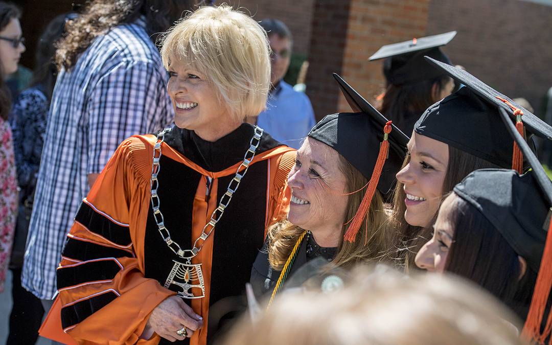 Dr. Lynne Murray posing for photo with students at graduation