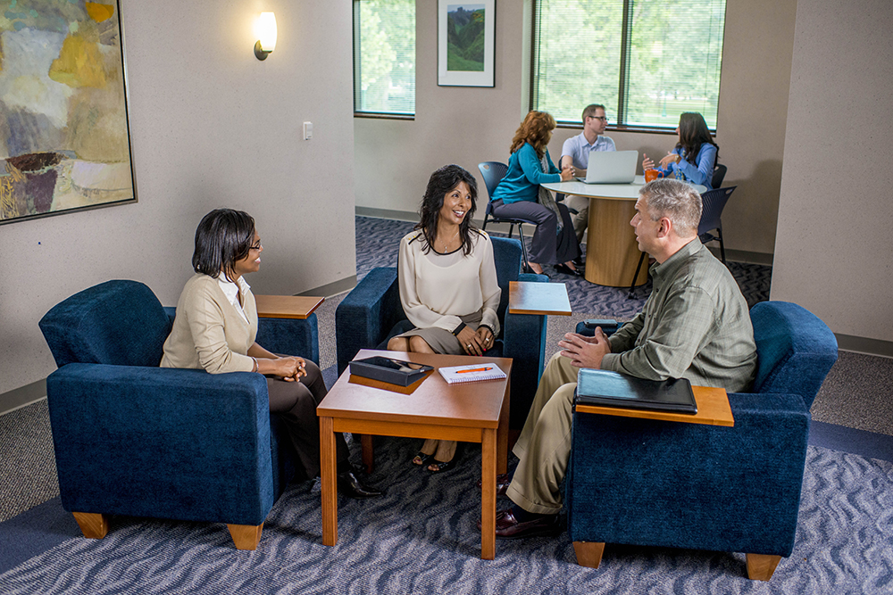 Three students sitting in chairs and talking
