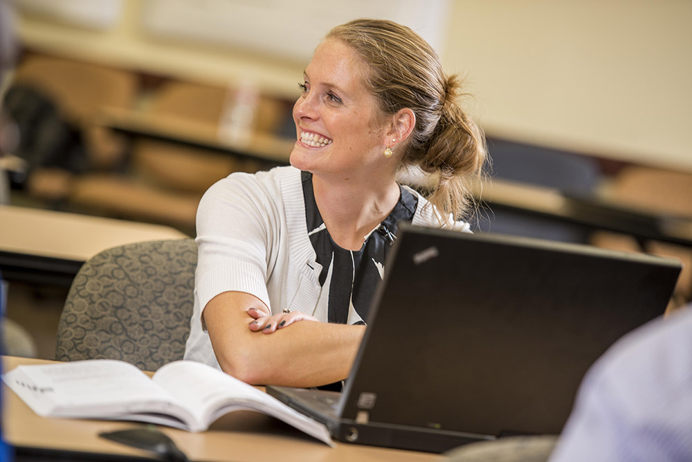 Adult student smiling while studying and working on a laptop