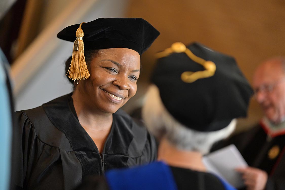 doctoral graduate student smiling in cap and gown