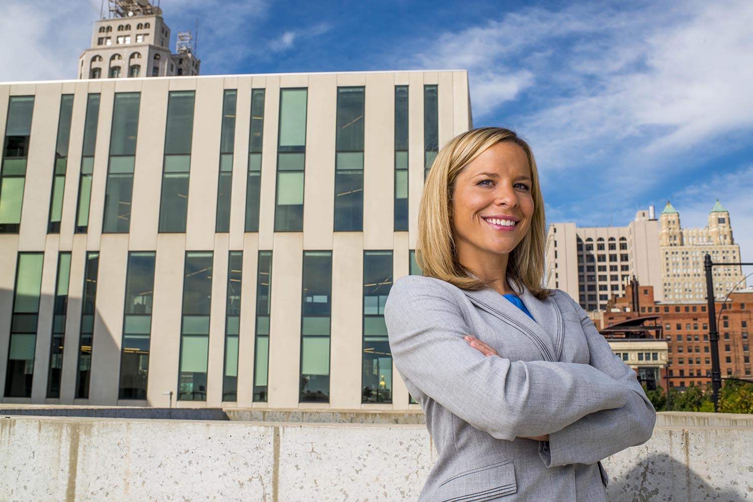 Kansas City business woman posing with arms crossed and smiling in front of office building