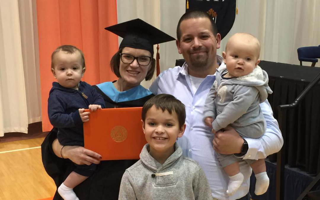 Graduate Nicole Robles with husband and three sons at commencement ceremony