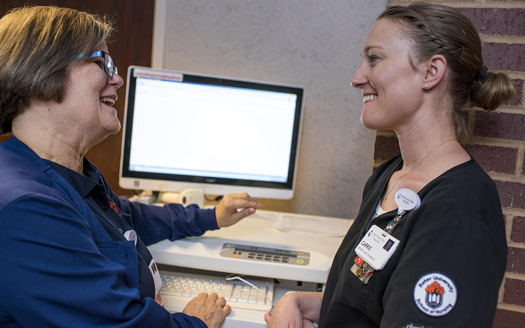 Nursing student talking with nursing professor at a computer