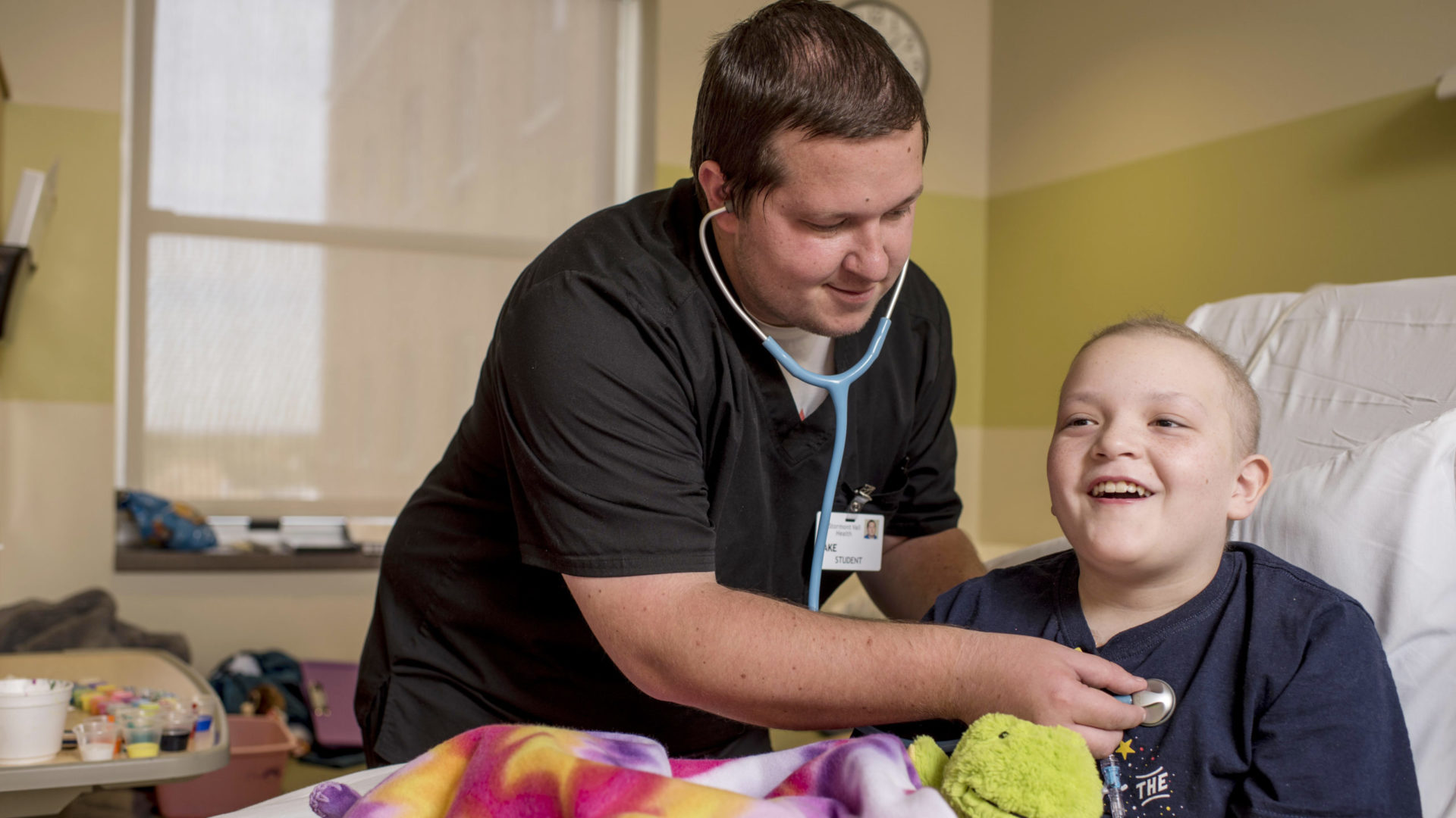 Nursing student using stethoscope to check heart beat of child patient