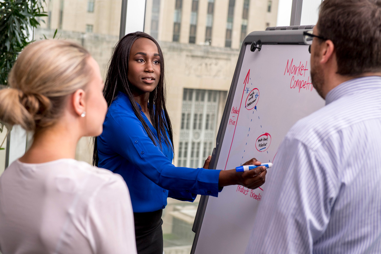 Business student using whiteboard to show classmates a master’s in instructional design project