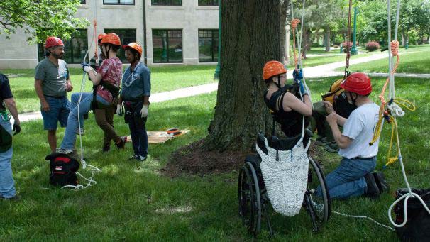 Students rope climbing a tree on campus