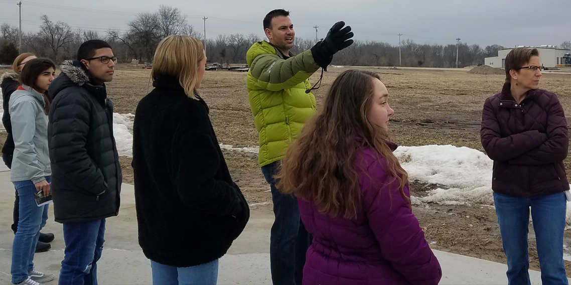 Biology students and professor looking at solar farm site.