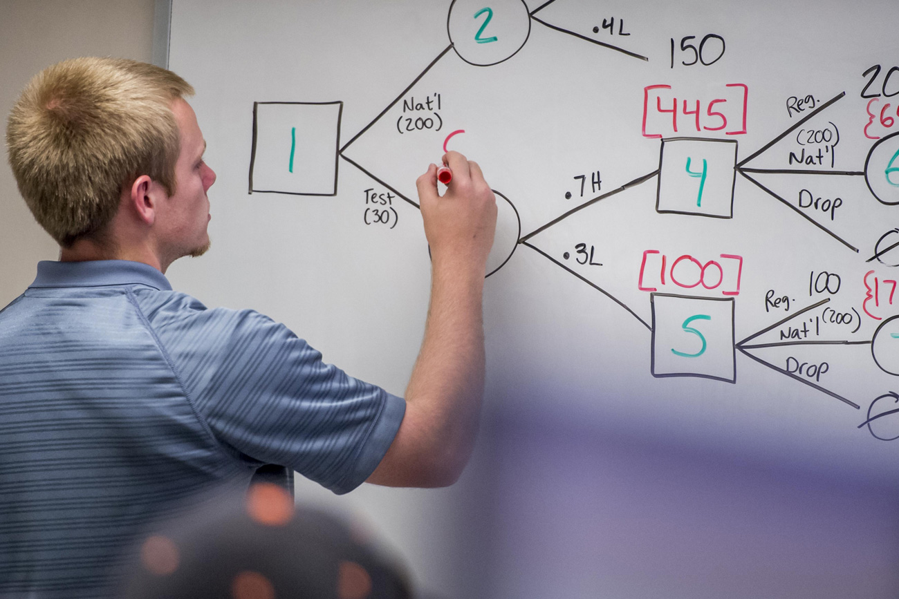 Business analytics student using whiteboard for calculations