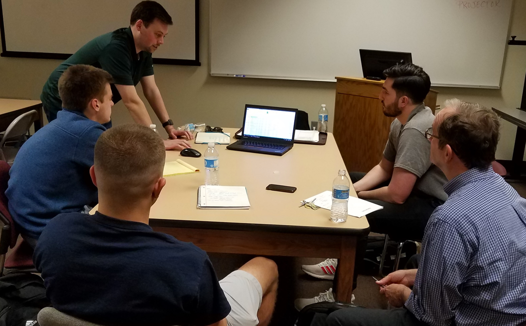 Business students and professor sitting around a table working on a project.