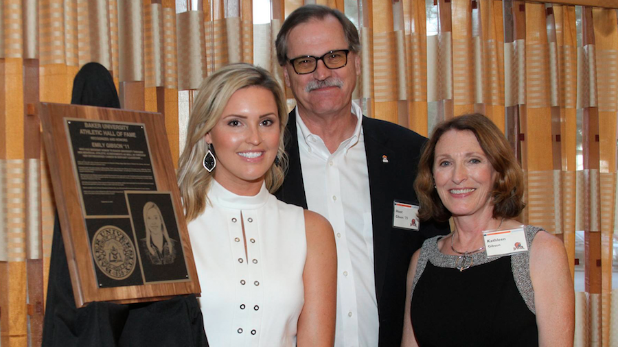 Emily Gibson and parents posing in front of her plaque at Athletic hall of fame