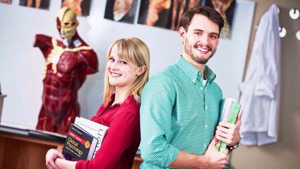 Two Students back to back holding textbooks