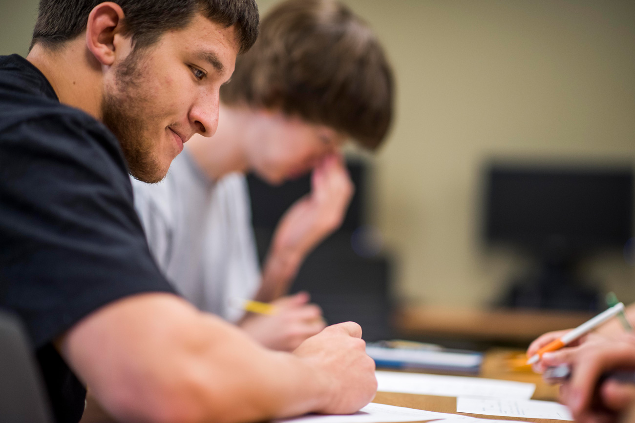 Male student sitting at desk working on a worksheet