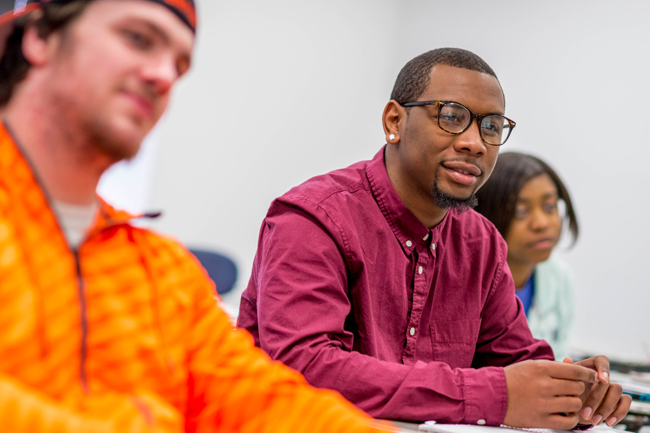 Three students listening to lecture in classroom