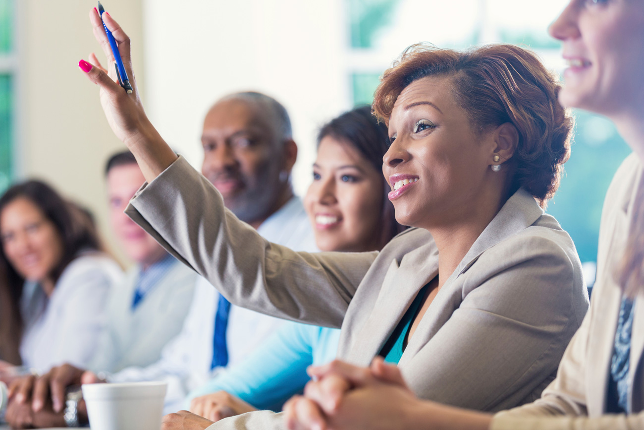 administrator in a meeting raising hand