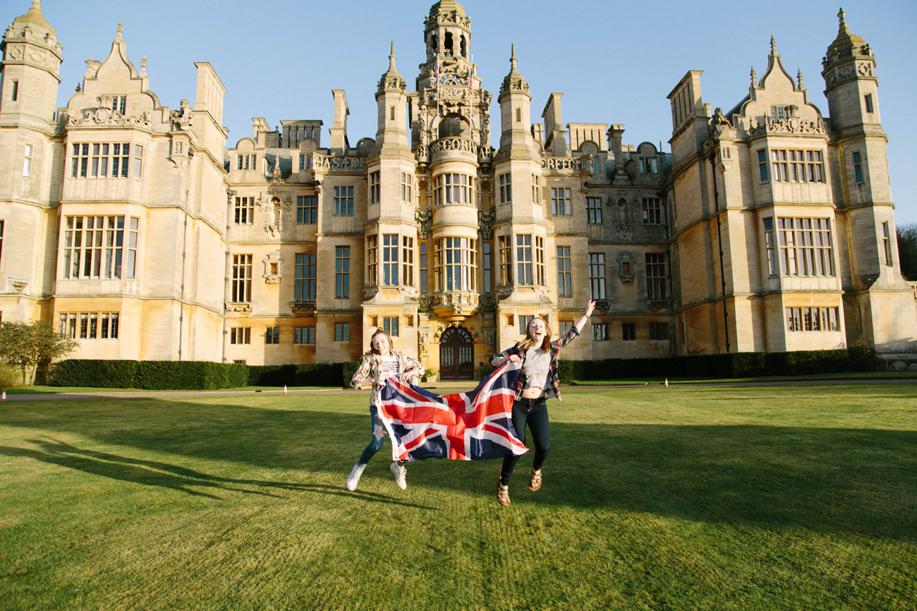 Students studying abroad at Harlaxton Manor jumping and holding a British flag