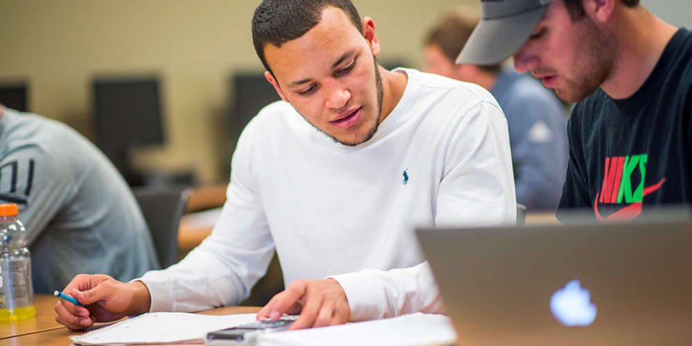 Students studying together with a laptop in the foreground