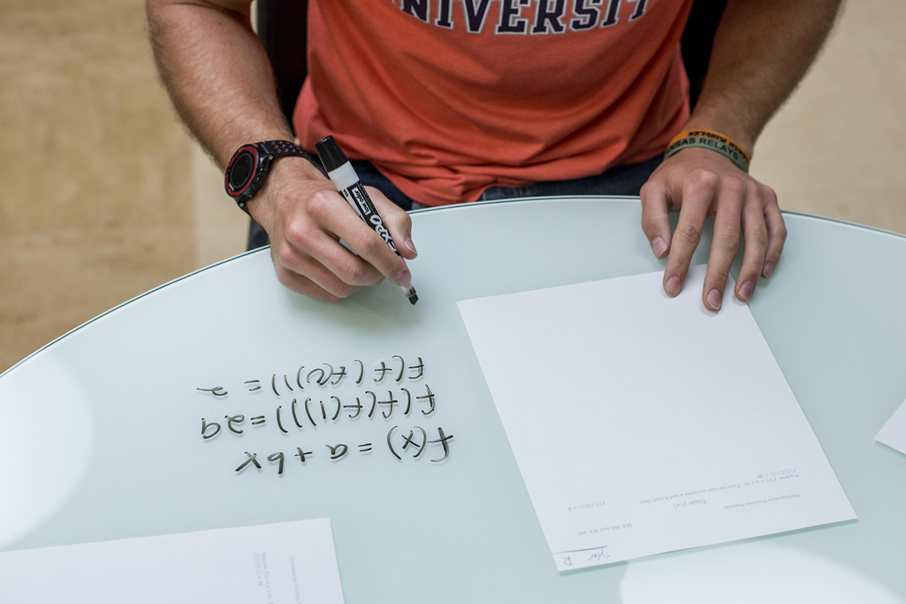 Student Solving A Math Program on a whiteboard desk with an Expo marker