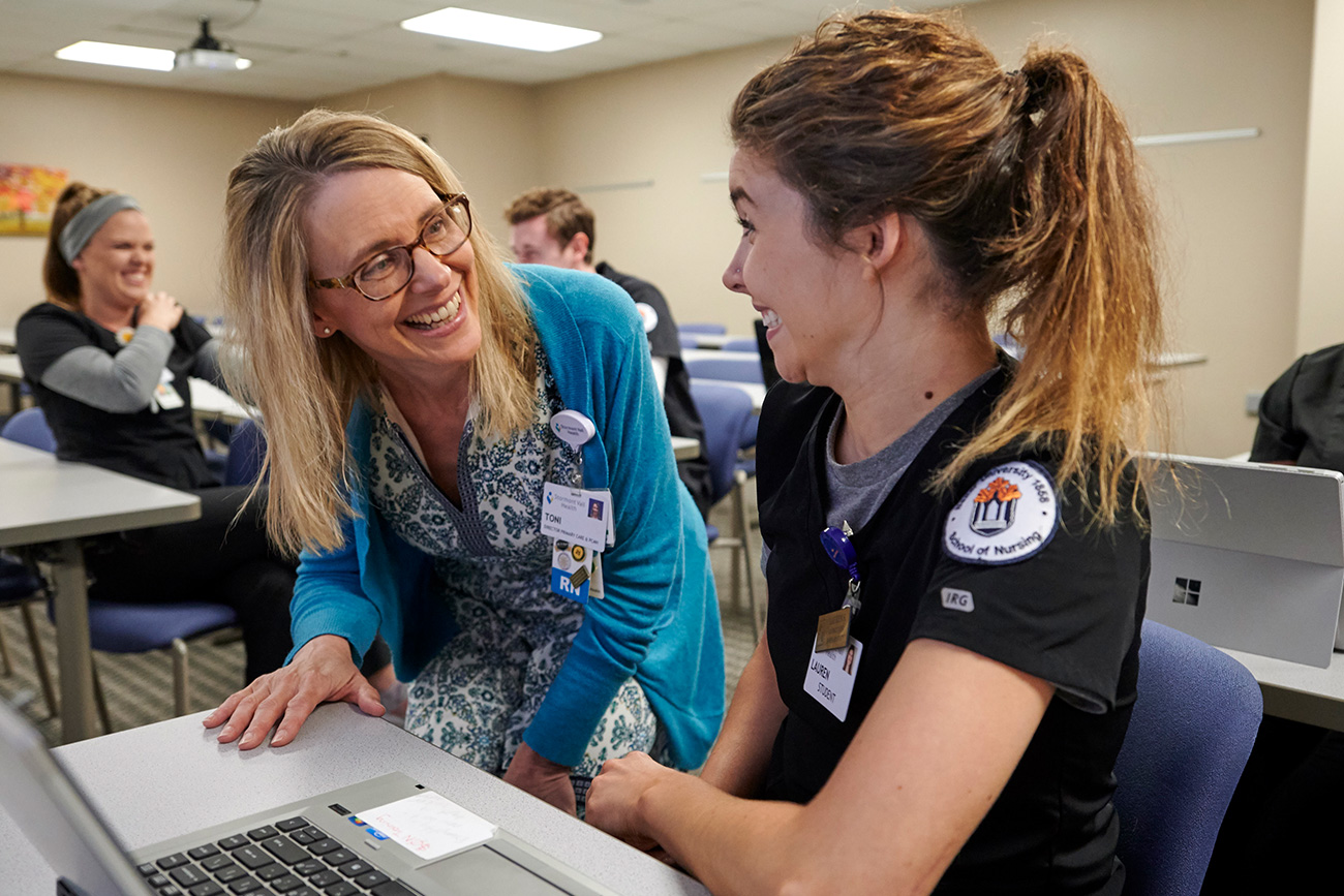 nursing professor talking one on one with female student in class