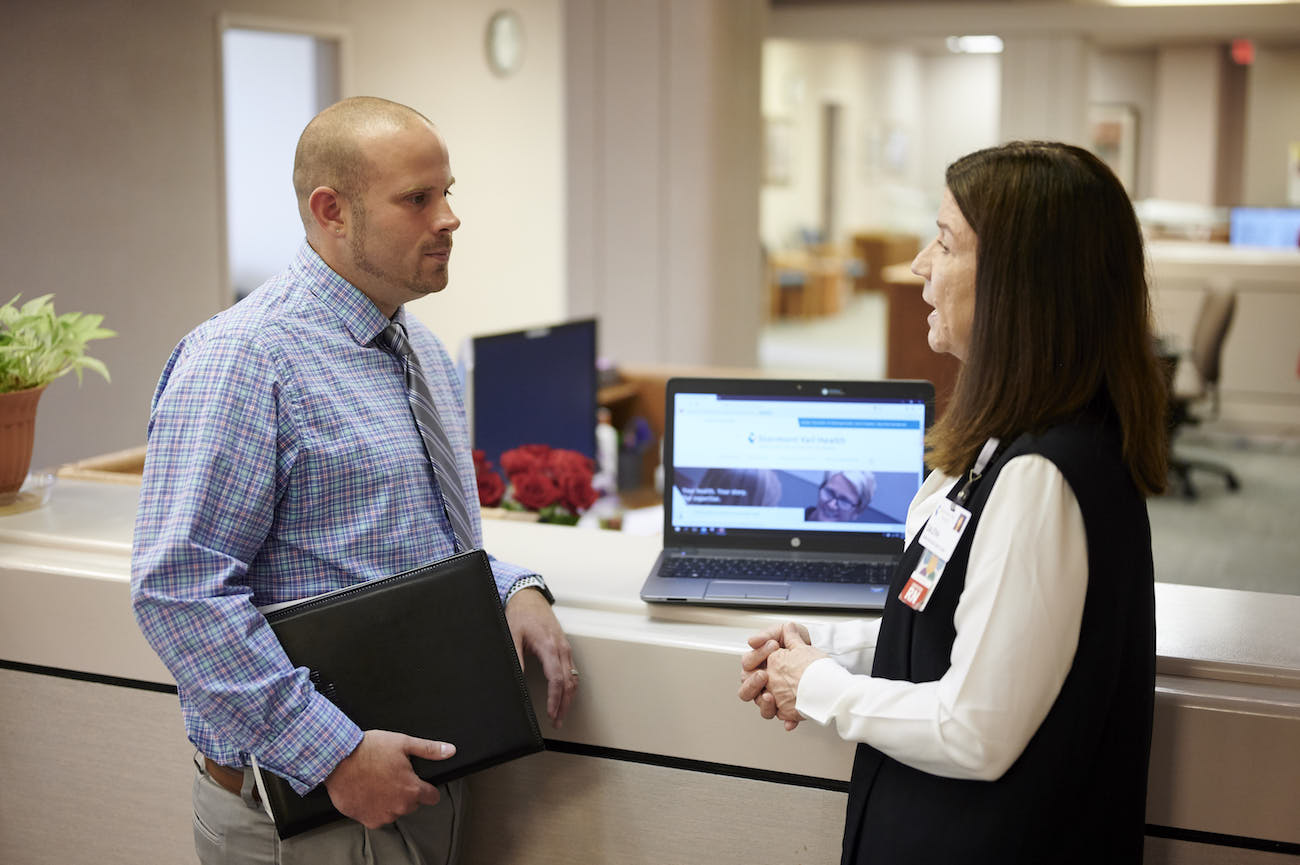 Male and female nursing administrators standing at a computer