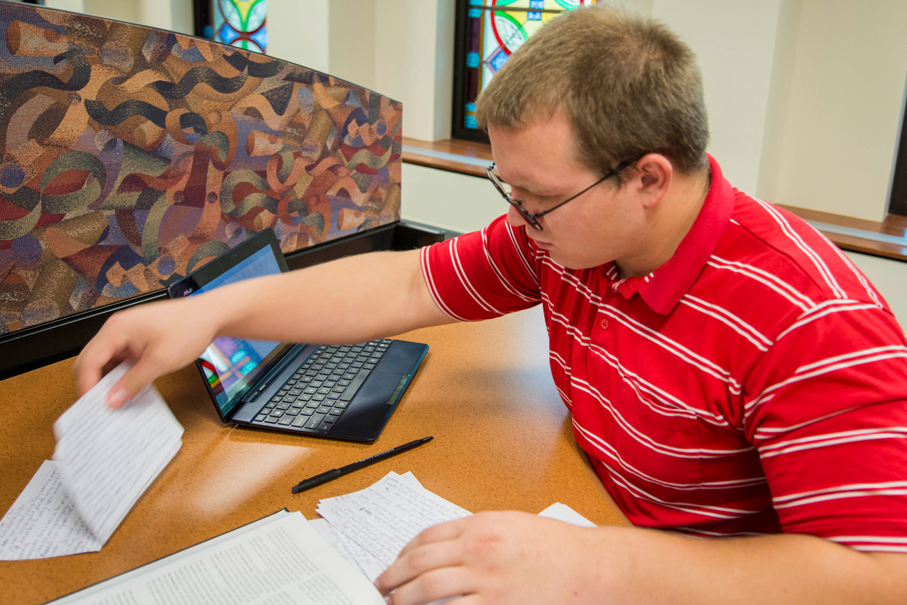 philosophy student studying at the library with a laptop and notecards