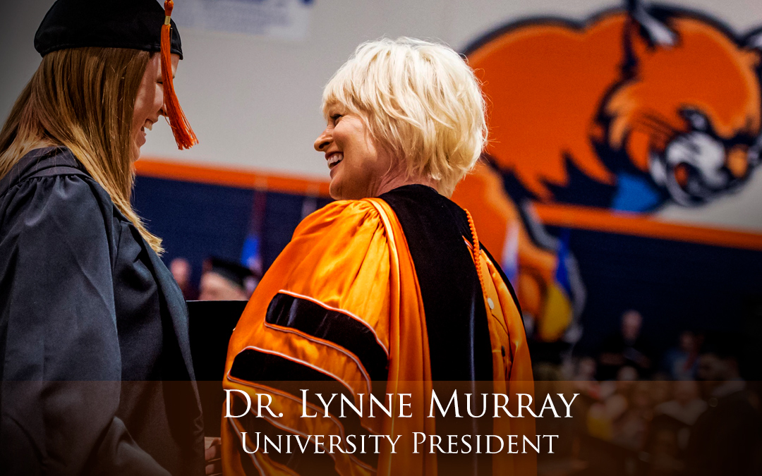 Dr. Lynne Murray, president, smiling at graduating student at commencement