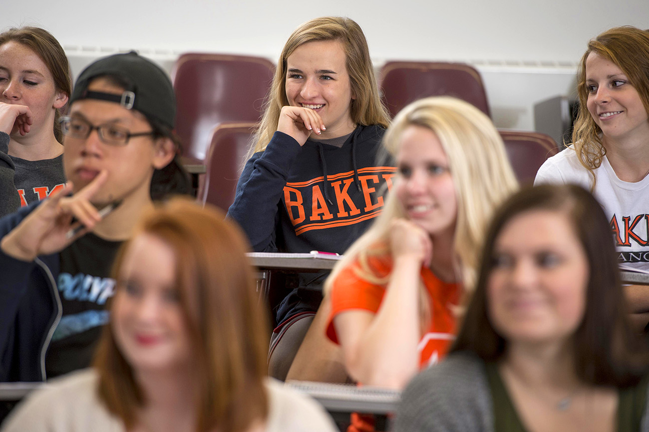 Students smiling and sitting in desks in the classroom