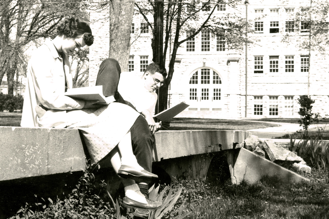 Black and white photo of students in the 1950s studying on the bridge by Mabee hall