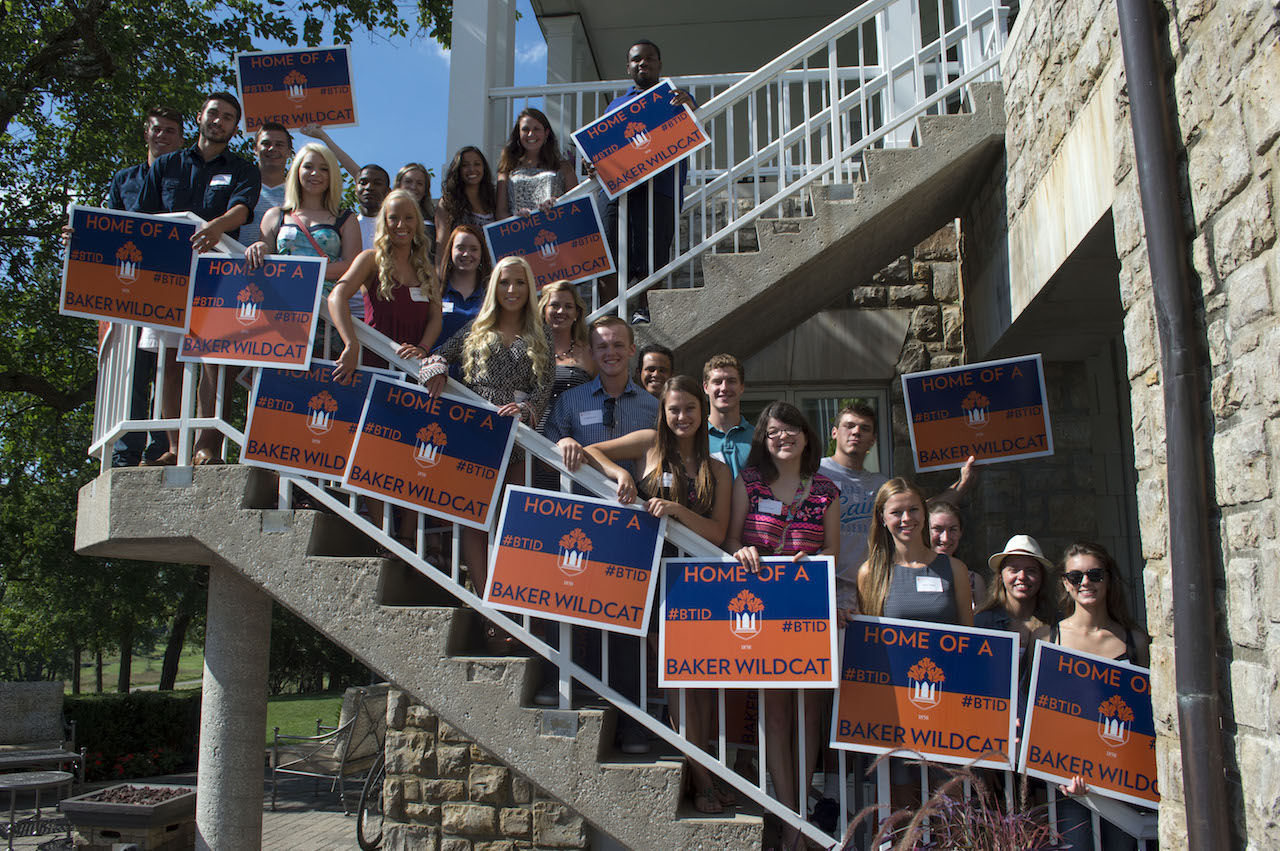 students on the stairs holding baker wildcat yard signs for summer sendoff