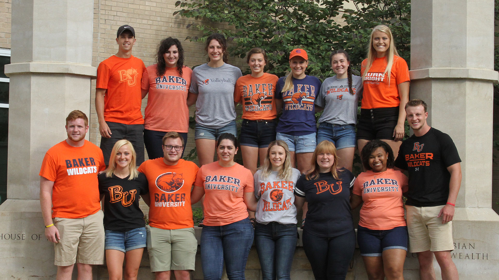 Group photo of student UAA's standing between two columns and wearing baker university shirts