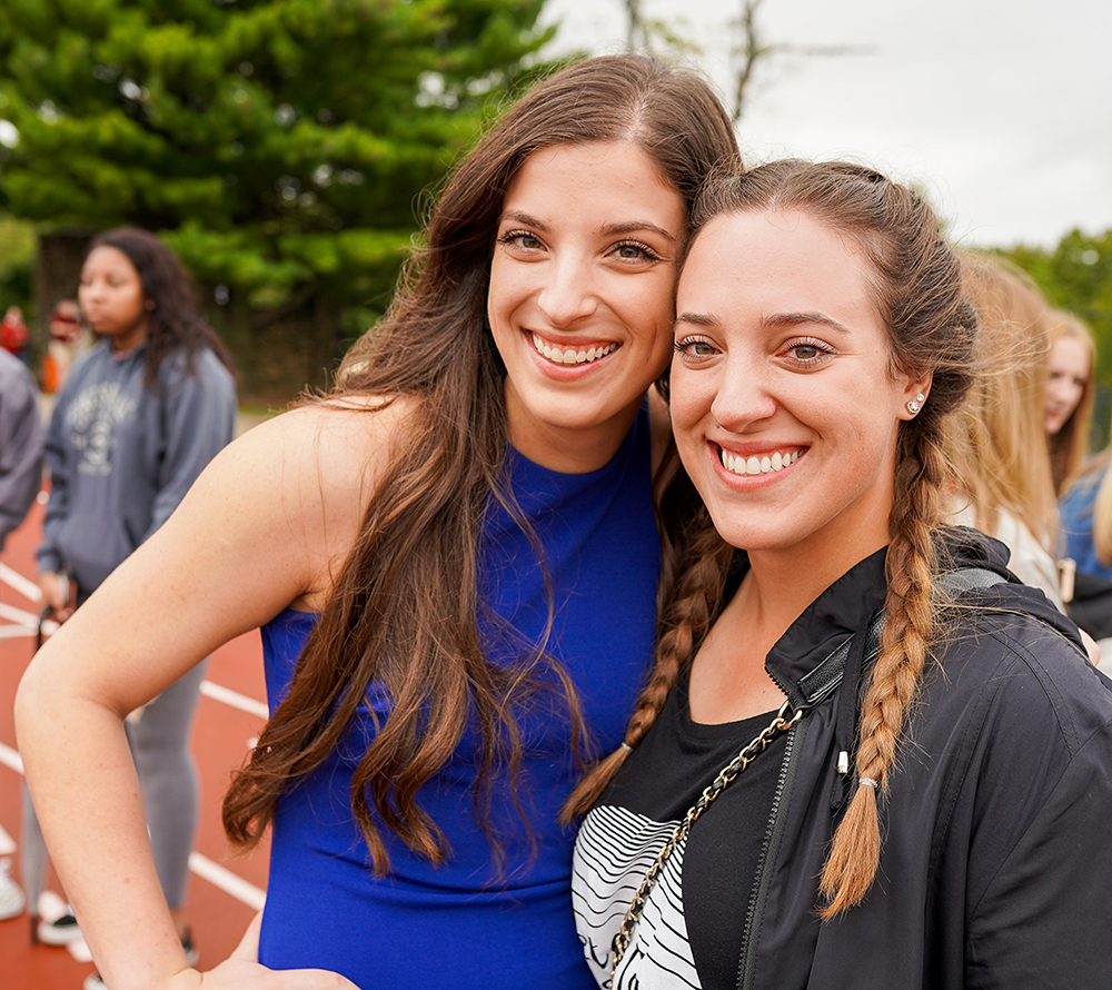 Two students standing on the track and smiling