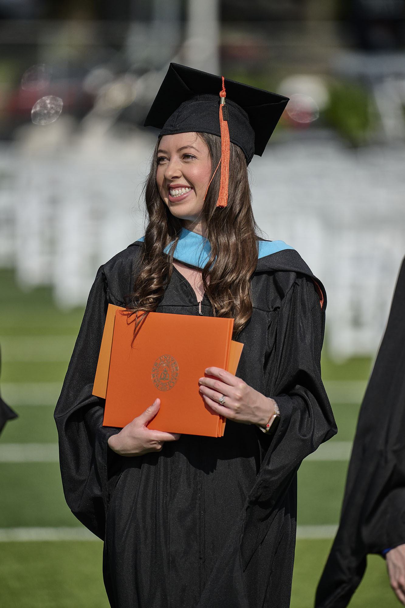 Female master's in education graduate in regalia holding diploma.