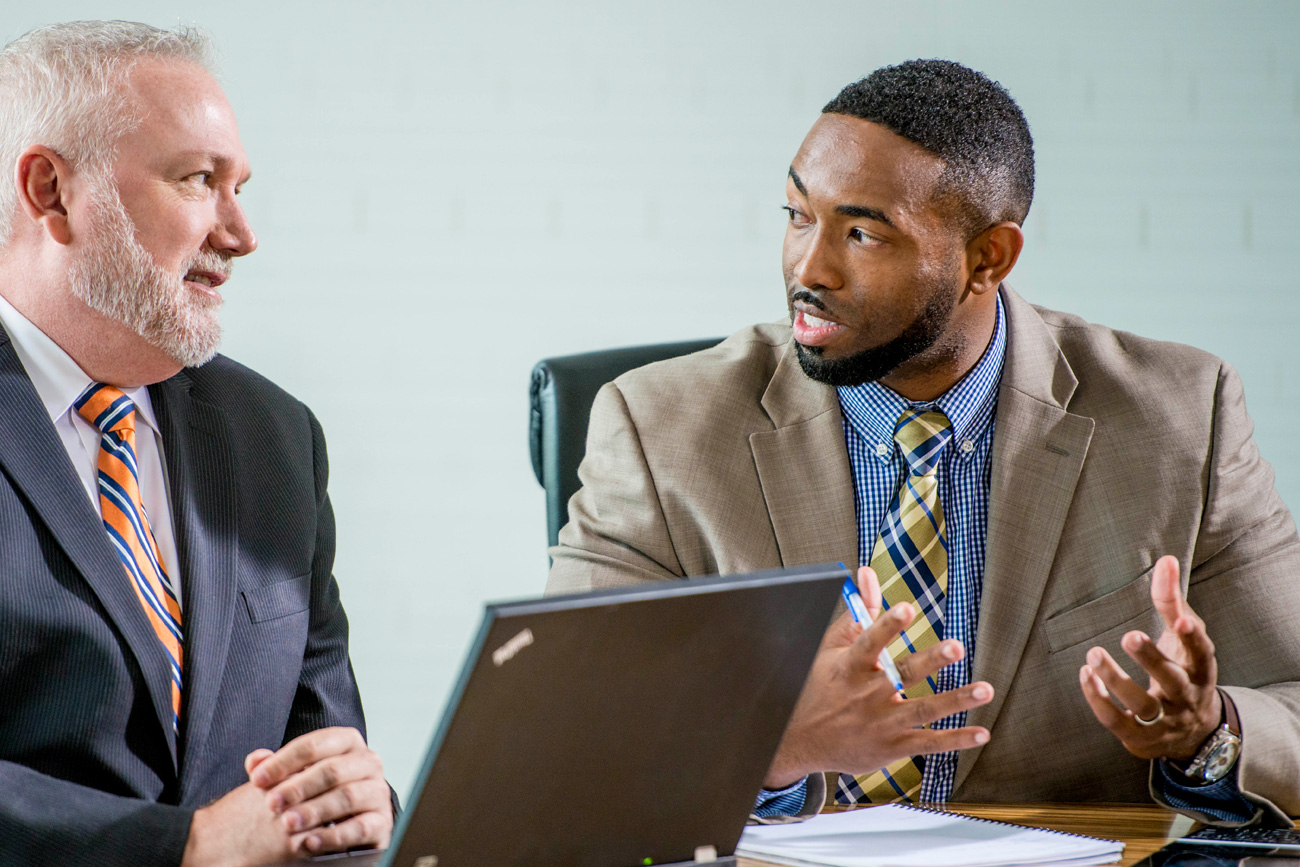 graduate business man speaking with a colleague at a table