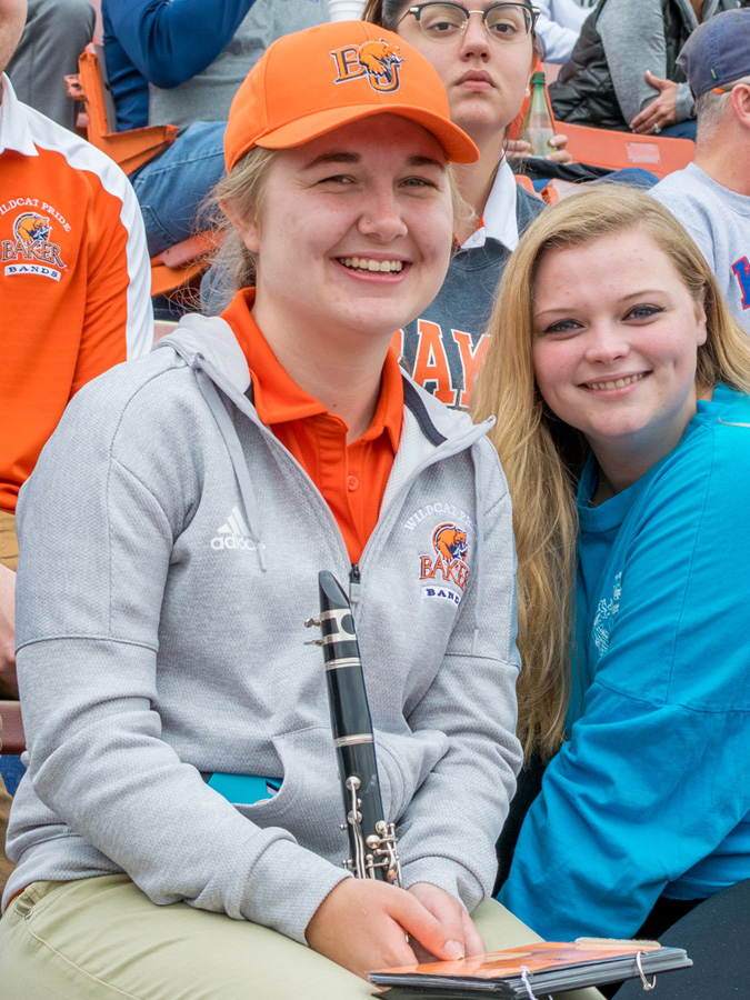 band student holding a clarinet and smiling at a football game